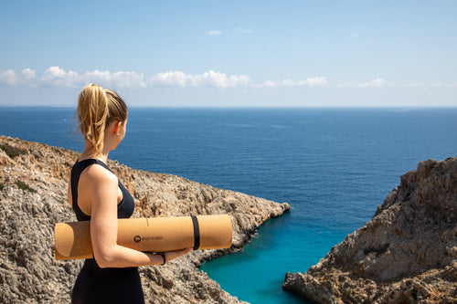 nadine am strand mit yogamatte aus kork in der hand