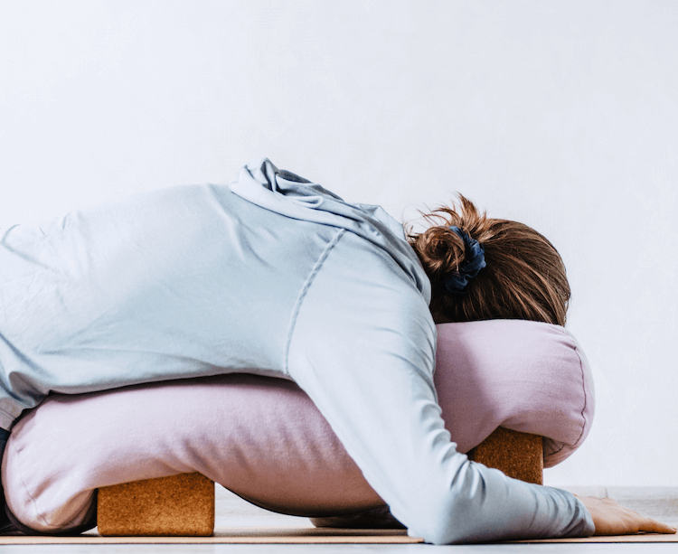 frau-liegt-yoga-matte-mit-block